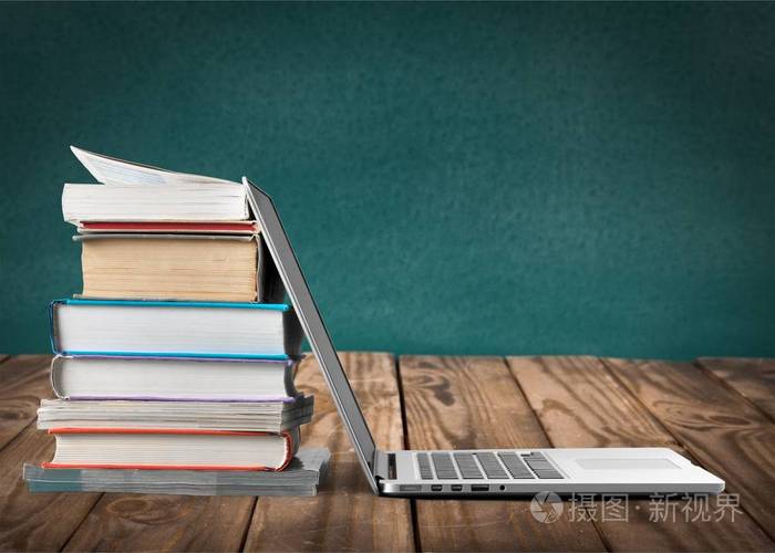 一摞书与笔记本电脑桌上