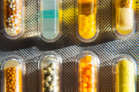 白色背景下透明药胶囊中各种彩色药丸的细节, 疾病医学概念