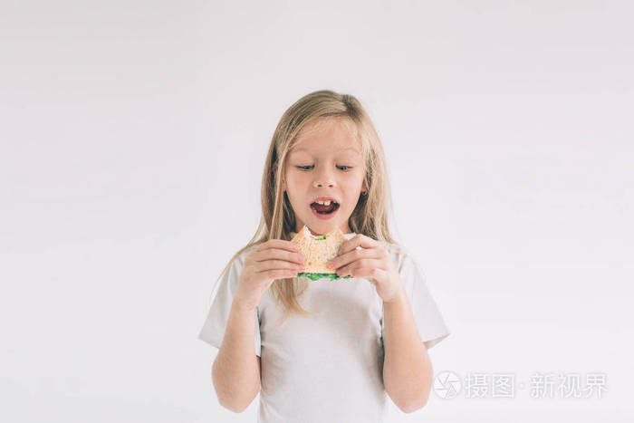孩子拿着一块汉堡包孩子吃快餐不是有用的食物非常饿的婴儿女孩在白色