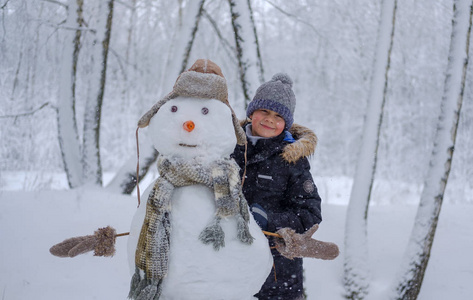 欧洲男孩和雪森林里的雪人