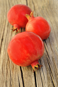 在木板上的三个新鲜红 pomegranetes