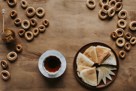 美味自制薄煎饼杯茶, 百吉饼和蜂蜜在木桌上