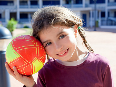 黑发的小女孩的足球运动员和球微笑