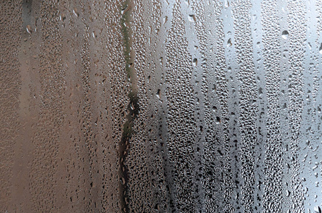 质地的一滴雨在玻璃湿透明的背景上.灰色色调照片