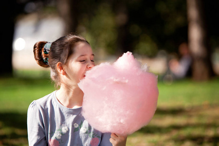 年轻的女孩在公园里吃棉花糖照片