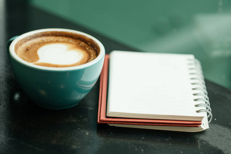 杯咖啡有气泡心形在上面与笔记本放置