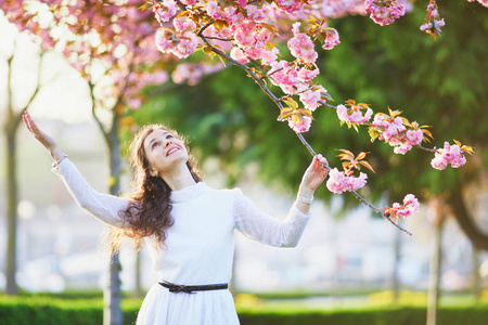 法国巴黎的樱桃花季节, 穿着白色连衣裙的快乐年轻女子