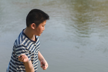 亚洲男孩投掷石头到水, 户外生活方式
