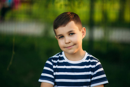 一个穿着条纹 t恤衫的小男孩站在绿色背景的前面.