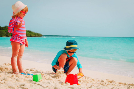 小男孩和女孩玩沙子中，在热带的海滩上