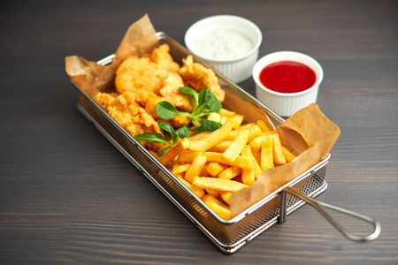 炸鸡块配薯条和木板上的不同调味汁照片