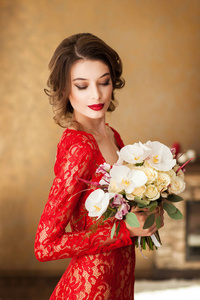 华丽的年轻女子优雅的红色蕾丝礼服捧花束