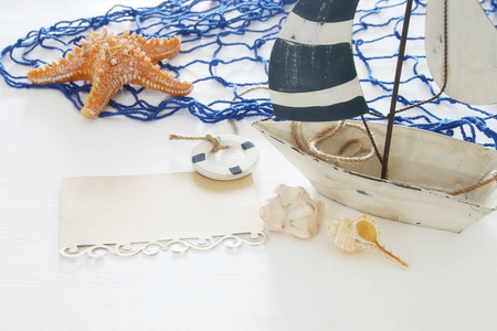 航海概念图片以白色装饰风帆小船, 海贝壳, 海星并且笔记在白色木桌