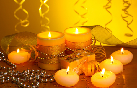 美丽的蜡烛，礼品和在黄色背景上的木桌上的装饰