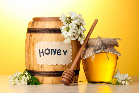 中桶 罐和相思鲜花在黄色背景上的木桌上的蜜
