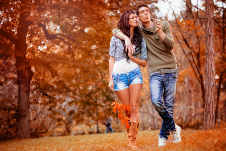 美丽可爱的情侣漫步在公园里欣赏秋天的色彩