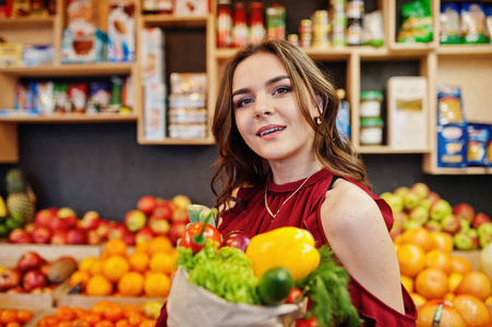 女孩在红色举行不同的蔬菜在果子商店