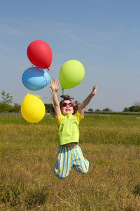 快乐的小女孩与气球在草地上跳