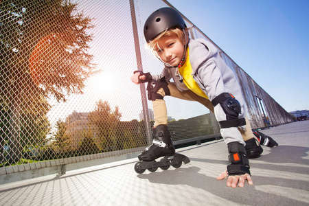 特写肖像青春期男孩, 轮滑运动员在防护装备, 摆在地板上在户外 rollerdrom