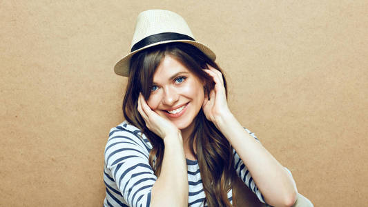 身穿条纹衬衫和时髦帽子的女人坐在米色墙背景