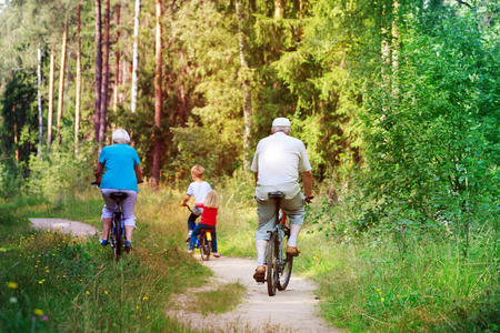 活跃的资深祖父母与孩子骑自行车在自然