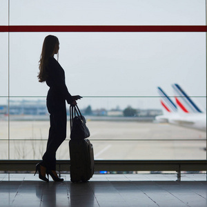 国际机场的年轻女子透过窗户看飞机