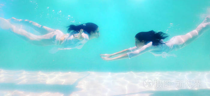 女人美丽的身体在水下游泳时穿白色礼服