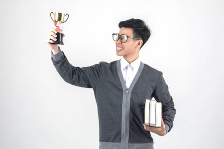年轻的书男子拿着奖杯 , 微笑着站在反对白背景