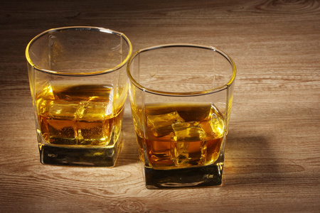 两杯苏格兰威士忌和木桌上的冰