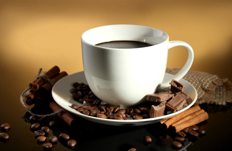 杯咖啡和咖啡豆 肉桂棒和巧克力棕色背景上