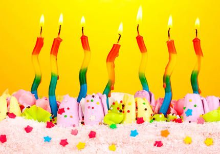 在黄色背景上的蜡烛的生日蛋糕图片