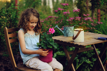 梦幻般快乐的儿童女孩在夏日傍晚的花园里放松, heranium 花在花盆里。教孩子们爱护自然, 爱护植物