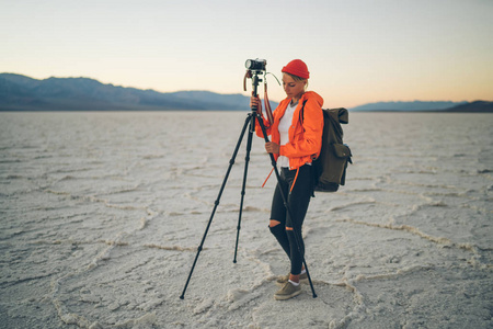 手持三脚架制作前的年轻女子恶水景观全景, 女摄影师用专业设备制作自然环境污染图片
