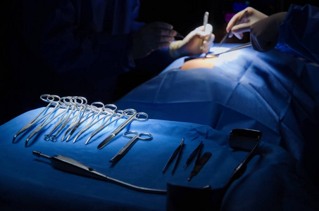 选择性聚焦手术器械躺在桌子上, 而外科医生组在手术室工作, 急诊, 外科, 医疗技术, 保健癌症, 疾病治疗的概念