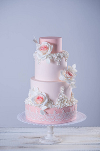 美丽典雅的四分层粉红色婚礼蛋糕装饰玫瑰花。糖胶的概念花