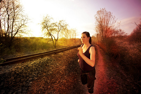 女孩在路上奔跑沿着铁轨和日落