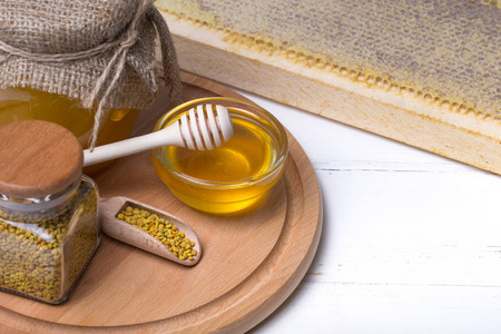 甜蜂蜜在玻璃碗和蜂胶在木背景