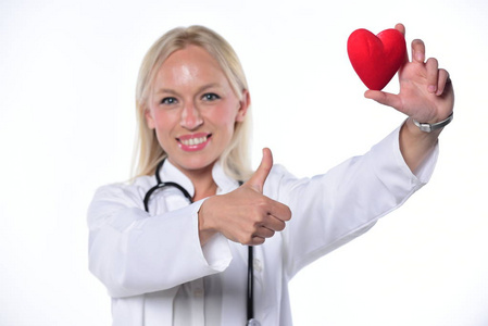 微笑的女医生抱着红色的心, 竖起大拇指。在白色背景上被隔离