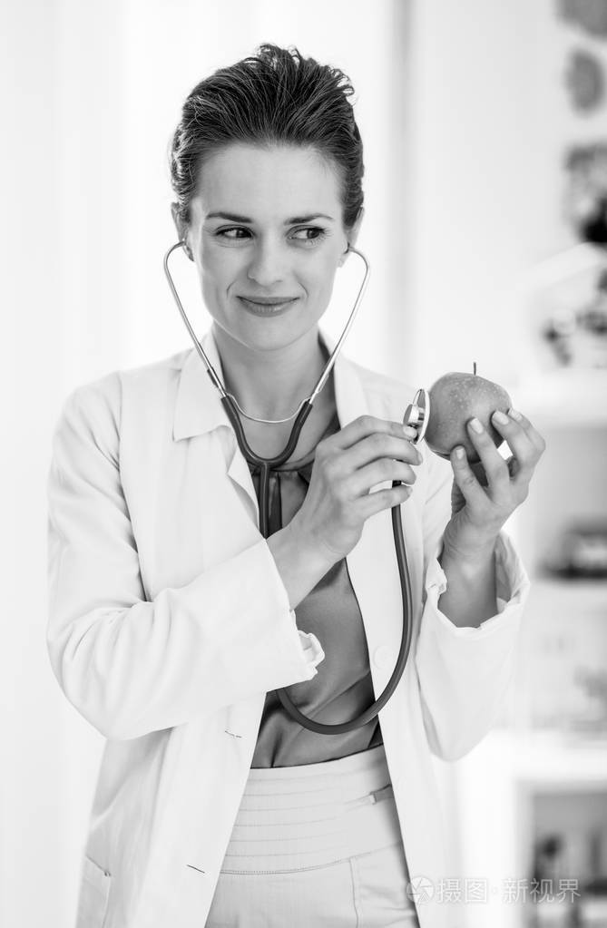 快乐的内科医生用听诊器检查苹果的女人照片-正版商用图片04nqvh-摄图