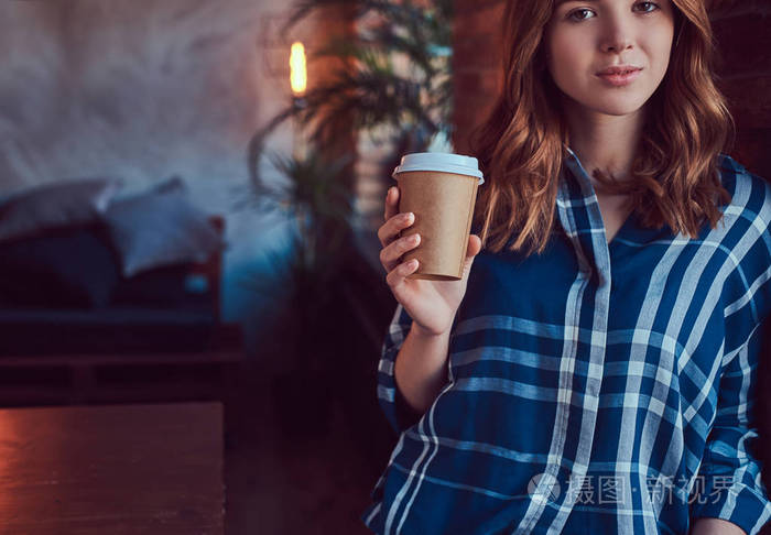 一个年轻的时髦女孩的肖像喝早晨咖啡与阁楼内饰