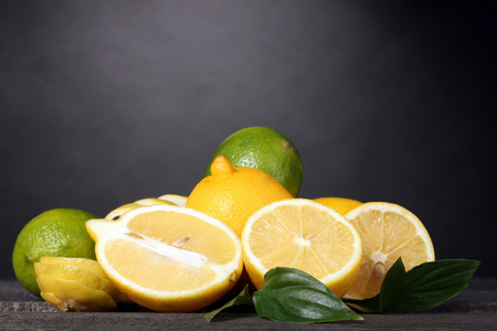 成熟的柠檬和酸橙与灰色的背景上的木桌上的叶子