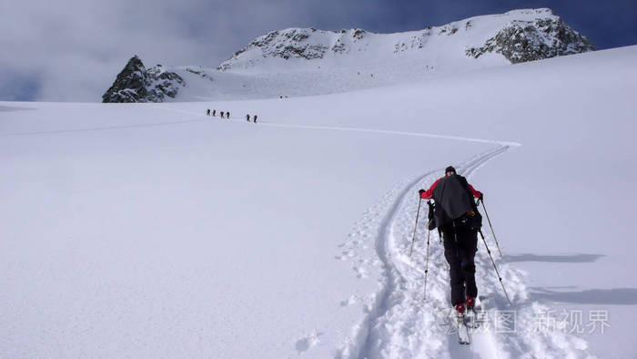 两个野外滑雪者在奥地利阿尔卑斯山巡回演出, 并在他们去山顶的路上投入新的足迹。