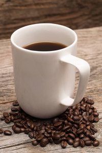 咖啡豆包围在白色的大杯, 对质朴的棕色谷仓木材背景拍摄