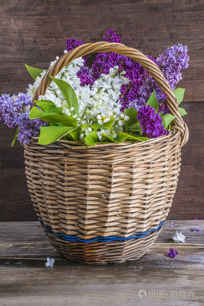 旧柳条篮子里的紫色和白色丁香花花束