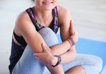 微笑的坐在瑜伽垫上后，在瑜伽锻炼瑜伽女人的画像。瑜伽。女人