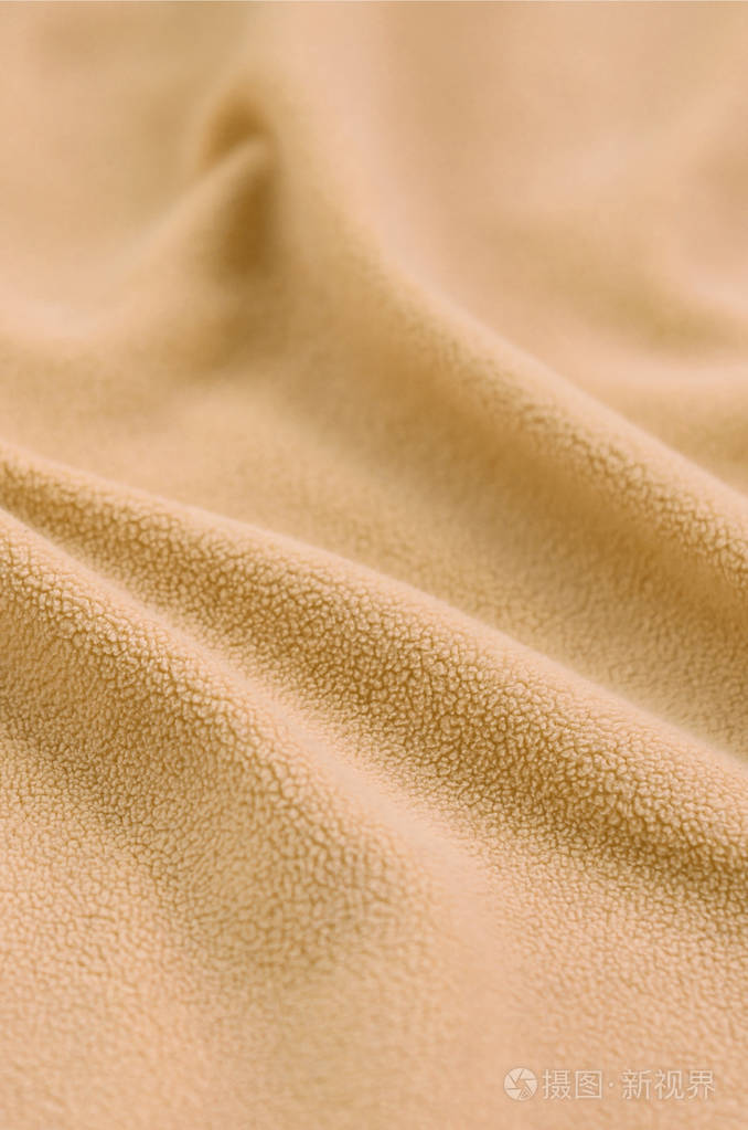 毛茸茸的橙色羊毛布的毯子浅橙色软毛绒绒材料的背景与大量浮雕褶皱