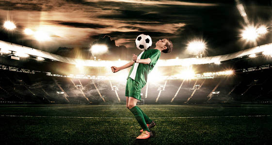 孩子足球运动员男孩向前在橄榄球运动服在体育场与球。体育概念