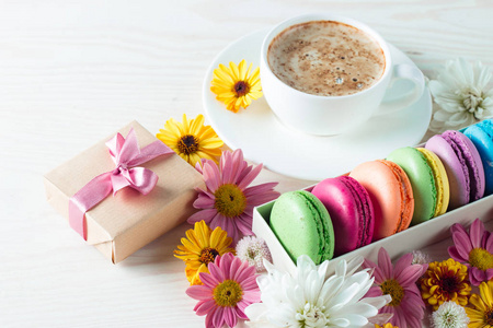 蛋糕马卡龙, 礼品盒, 茶, 咖啡, 卡布奇诺和鲜花的照片。甜蜜浪漫的食物杏仁概念。早餐和礼物