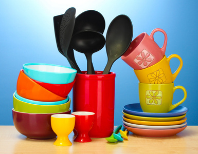 明亮的空碗 杯子和在蓝色背景上的木桌上的厨房用具