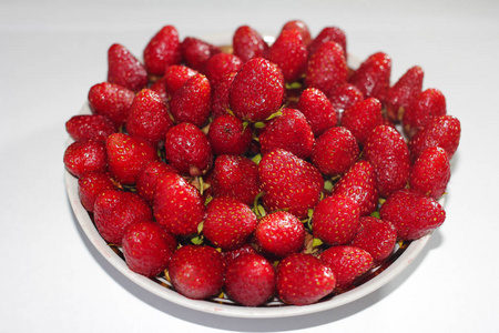一个新鲜的, 开胃的草莓排在一个圆盘子上的幻灯片。白色背景。特写